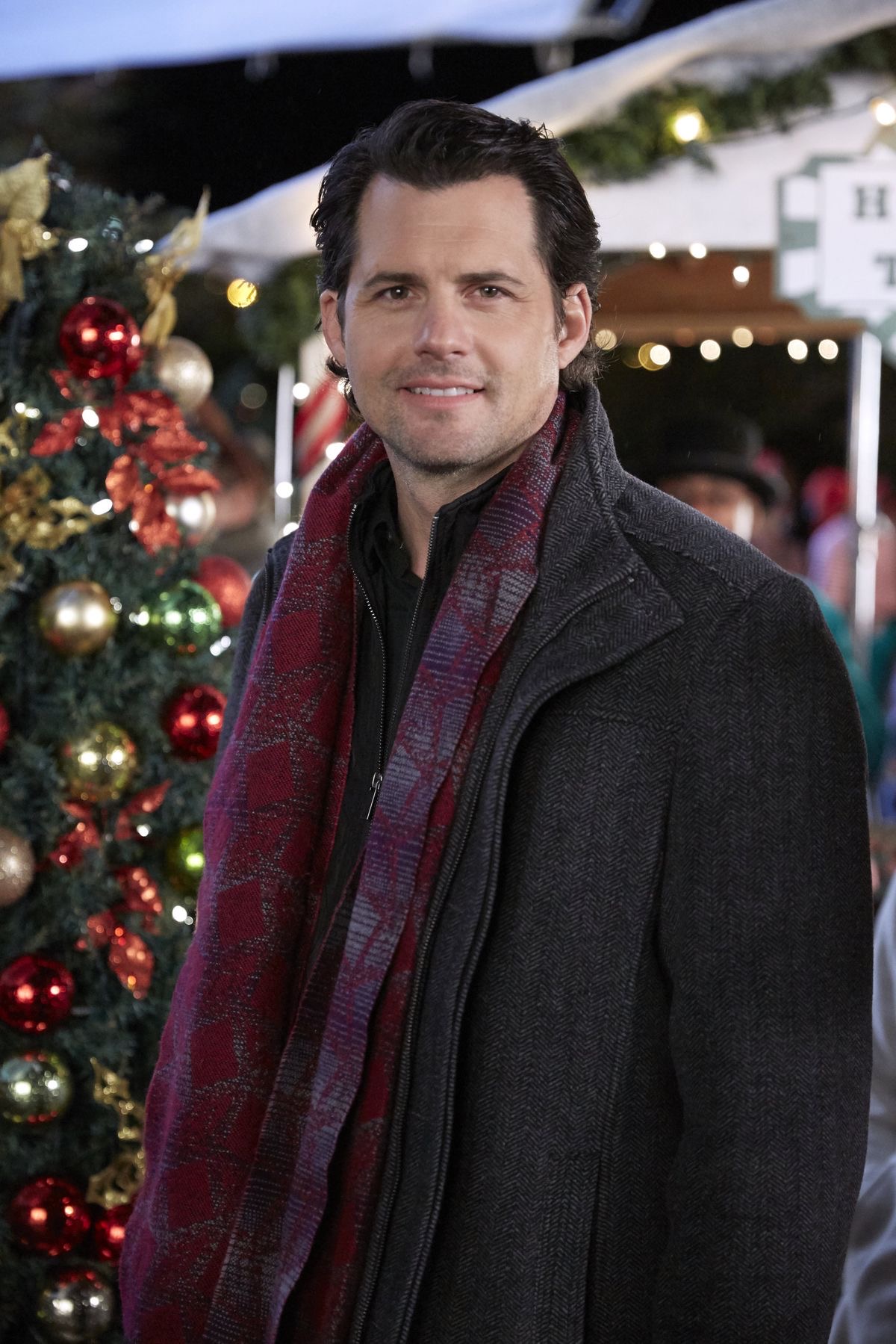 Kristoffer Polaha in a herringbone coat and scarf at a winter market